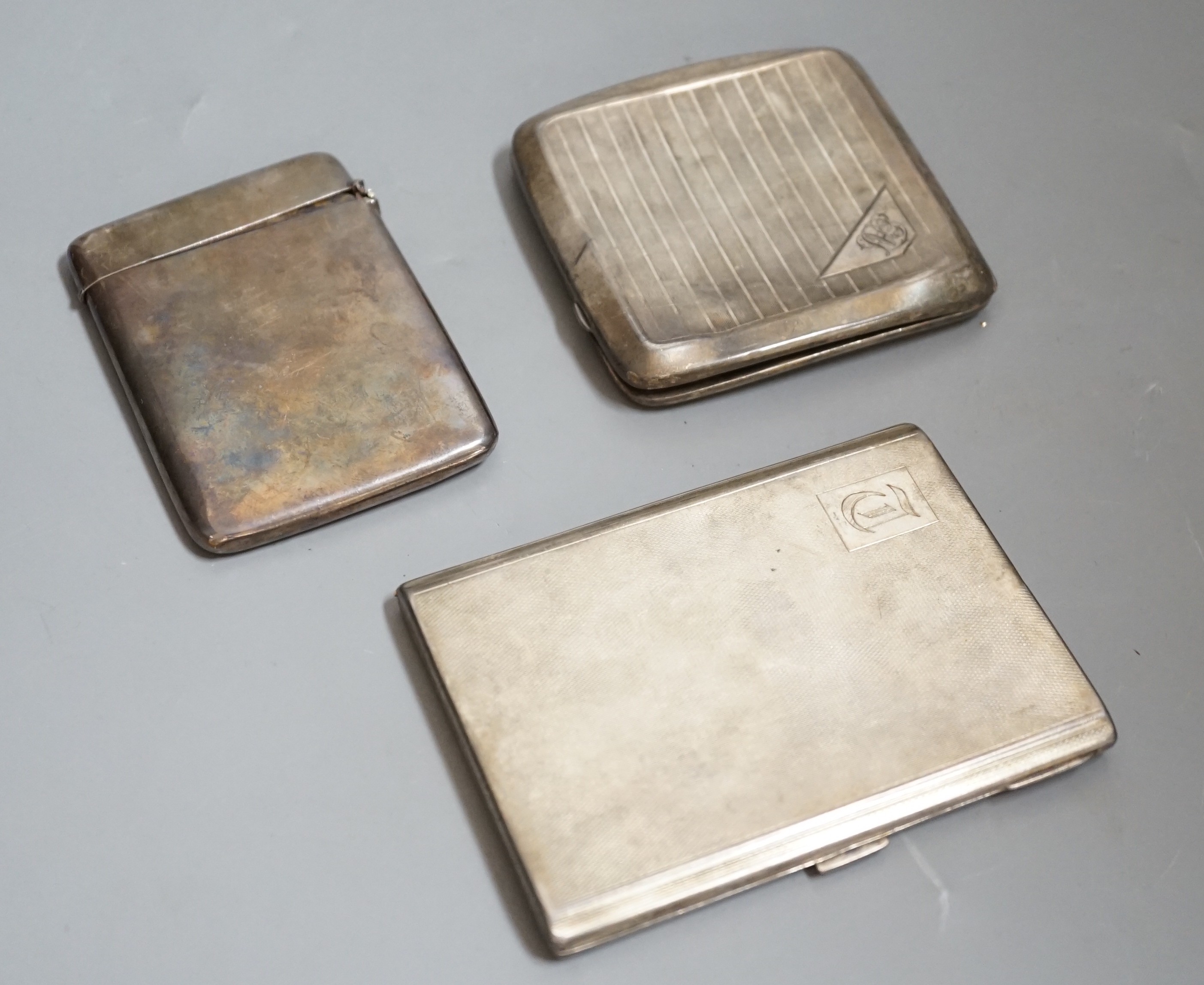 A George V engine turned silver cigarette case, 11.4cm, one other silver cigarette case and a silver card case with damaged lid.